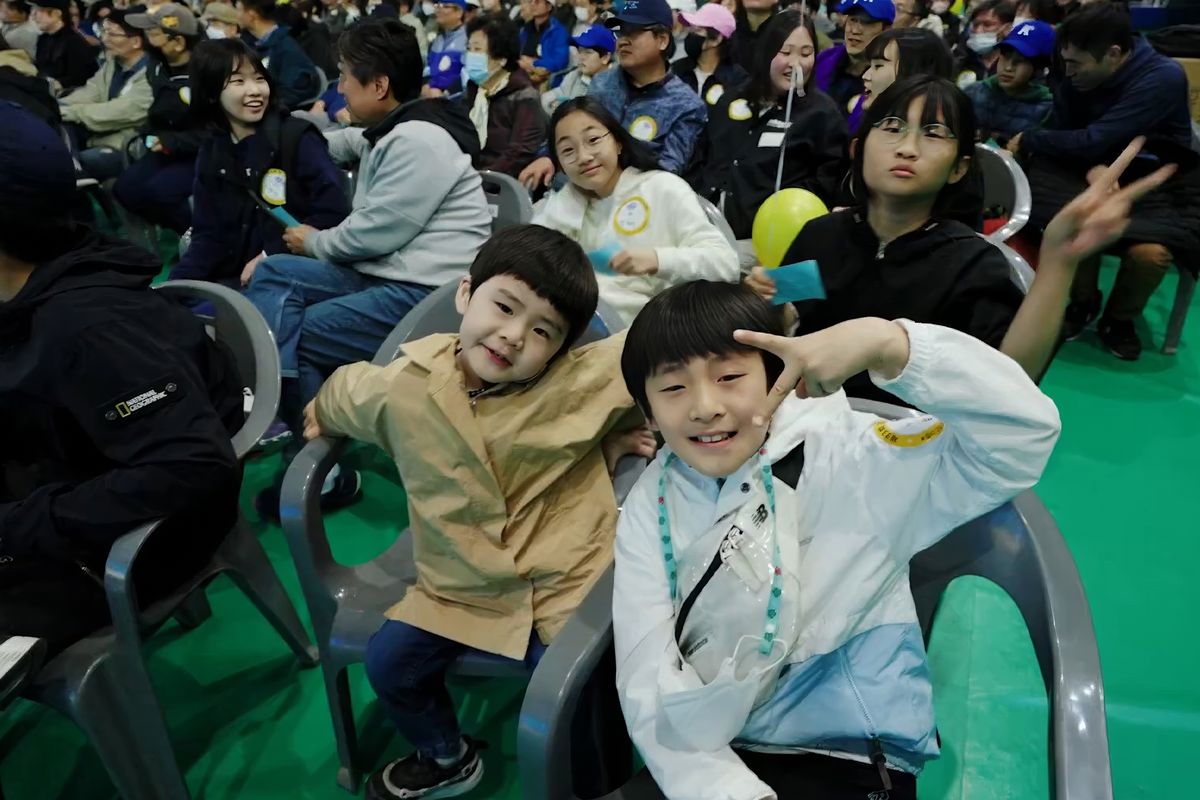 객석에서 손가락 브이를 그리며 웃는 어린이 관객들