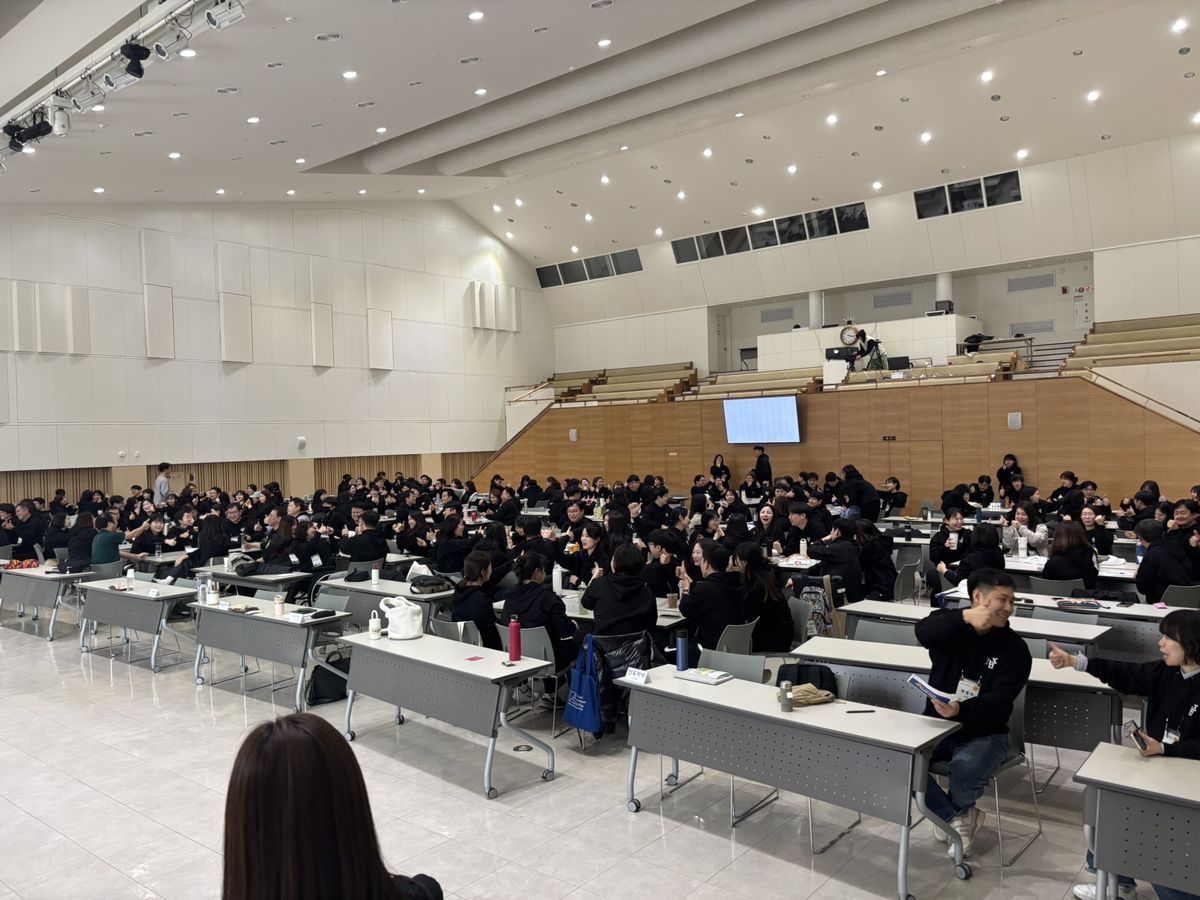 대강당 좌석에 앉아 단체 레크리에이션에 참여하는 참가자들